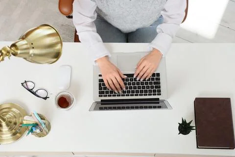 Overhead view of womans hands typing on laptop keyboard at white desk with of Stock Photos