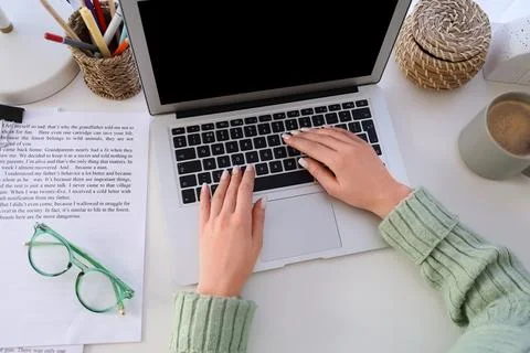 Overhead view of womans hands typing on laptop keyboard with coffee mug and d Stock Photos