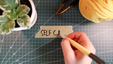 Overhead view of writing SELF CARE on tape with plant and tea cup. Stock Footage 338183799
