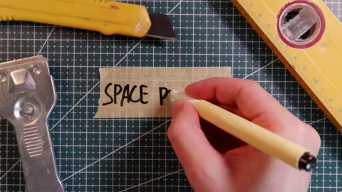 Overhead view of writing SPACE PLANNING on tape with tools. 스톡 동영상 337816253