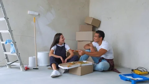 Overhead view of young couple eating pizza while sitting on floor in new Stock Footage 112872222