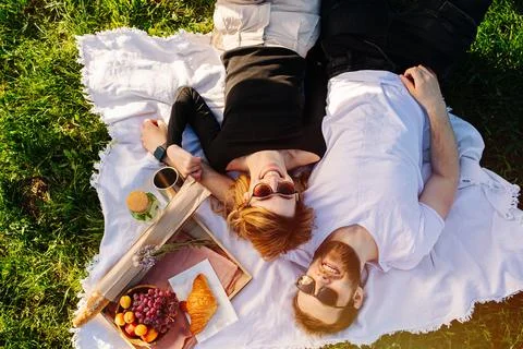 Overhead view of a young couple lying on a picnic blanket on a spring grassfi Stock Photos
