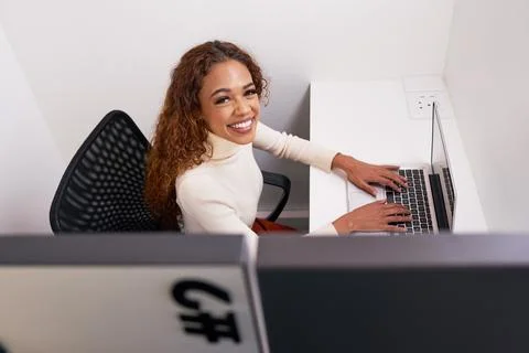 Overhead view of young multi-ethnic woman typing on laptop in private cubicle Stock Photos