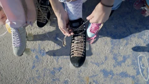 Overhead view of young women’s hands tying laces on retro rollerskates Stock Footage 197632287