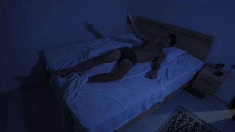 Overheated man uses air conditioner remote control to cool bedroom while Stock-Footage 346251367