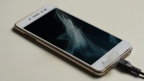 Overheating Smartphone Smoking While Charging on White Surface Stock Footage 327795604