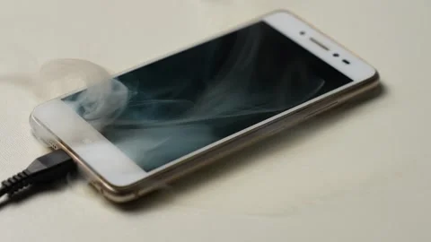 Overheating Smartphone Smoking While Charging on White Surface Stock Footage 327795608