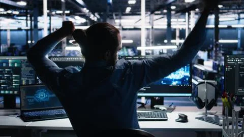 Overjoyed data center engineer dancing on chair after implementing AI Stock Photos