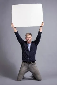 Overjoyed man holding up white empty signboard. Stock Photos