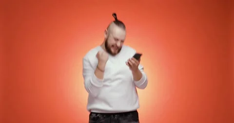 Overjoyed young bearded man is looking on smartphone doing winner gesture. Video stock 149034573