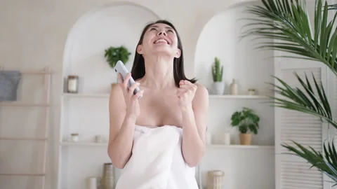 Overjoyed young multi ethnic asian girl in towel celebrating bid win success Stock Footage 156520391