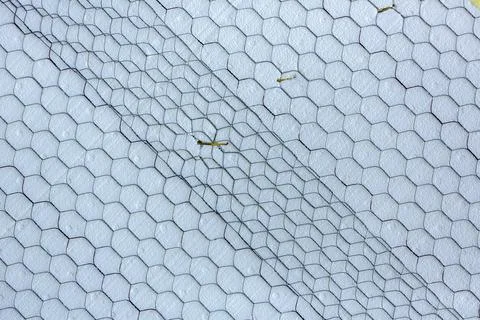 Overlapping panels of construction mesh over a white foam surface Foto stock