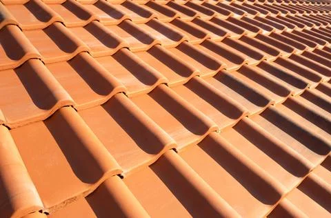 Overlapping rows of yellow ceramic roofing tiles covering residential buildin Stock Photos