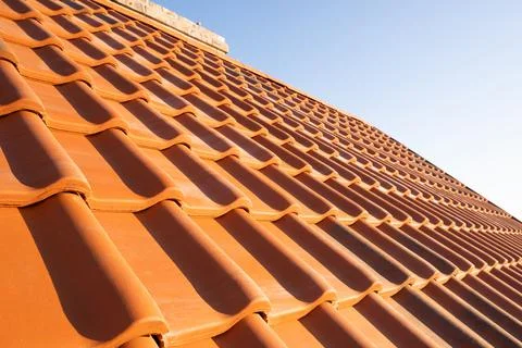 Overlapping rows of yellow ceramic roofing tiles covering residential buildin Foto stock