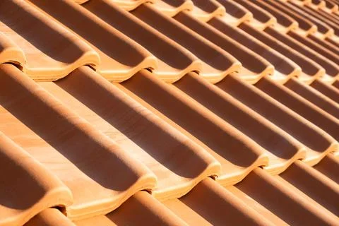 Overlapping rows of yellow ceramic roofing tiles covering residential buildin Stock Photos