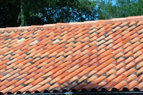 Overlapping rows of yellow ceramic roofing tiles covering residential buildin Stock Photos