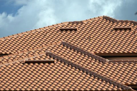Overlapping rows of yellow ceramic roofing tiles covering residential building Foto stock