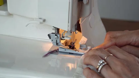 Overlock Serger sewing machine closeup. Asian Seamstress hands. Stock Footage 138692499