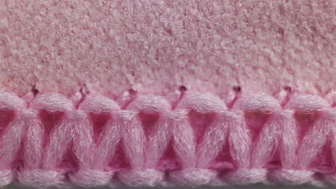 Overlock-treated edge of a very dense pink microfiber fabric. Real time, camera Stock Footage 129147570