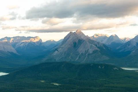 Overlooking a valley of trees with mountains and clouds in the background. Stock Photos