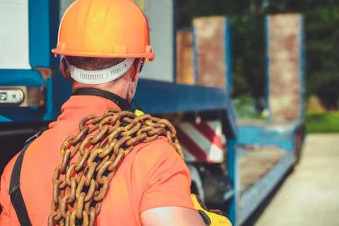 Oversize Load Concept. Caucasian Worker with Large Chain on His Shoulder.  库存照片