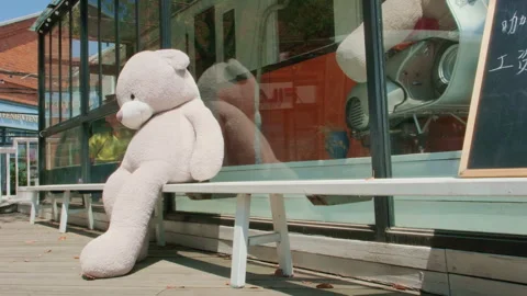 Oversized beige teddy bear next to glass storefront, close-up Stockbeeldmateriaal 332852750