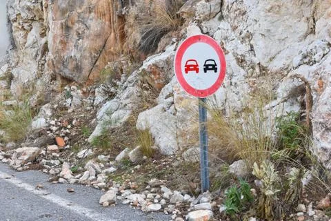 Overtaking sign is prohibited in the mountains, the danger of rock collapse. Stock Photos