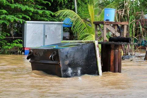 An overturned garbage can washed away by floodwaters Stock Photos