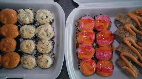 Overview of baked sushi rolls in delivery containers, Asian street food close-up Video stock 338186573