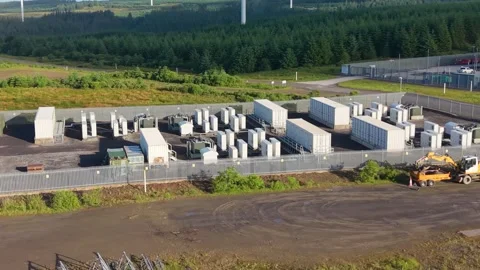 Overview of BESS Battery System Storage Containers with Wind Farm in Background. Stock Footage 337976552