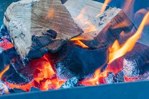 Overview of a fire pit with burning logs, warm hues orange, yellow, red, bl.. Stock Photos