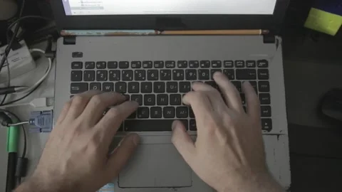 Overview shot of a man typing on a old notebook in a messed table  Stock Footage 160359238