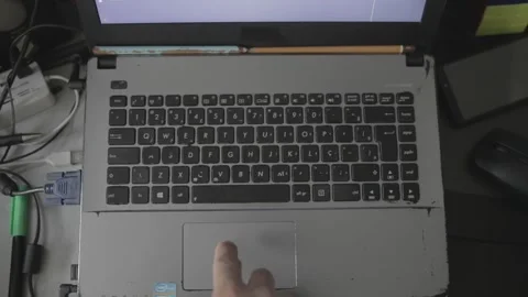 Overview shot of a man using a touchpad on a old notebook in a messed table  Stock Footage 160359258