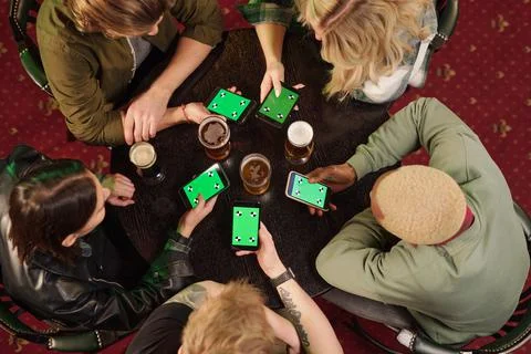 Overview of young friends using their smartphones with green coupons on screens Stock Photos