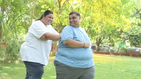 Overweight couple having fun together at summer park. Fat woman pushing man.. Stock Footage 312908201