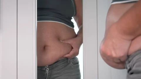Overweight female checking belly fat in mirror reflection Vidéo 316091252