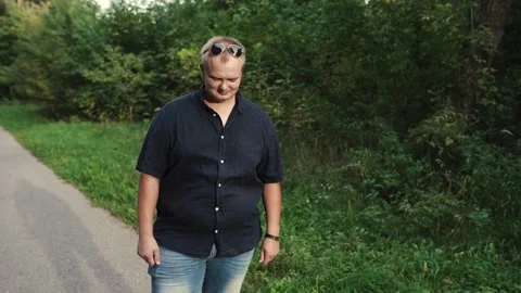 Overweight guy looks at the camera against the background of the forest Stock Footage 131461504