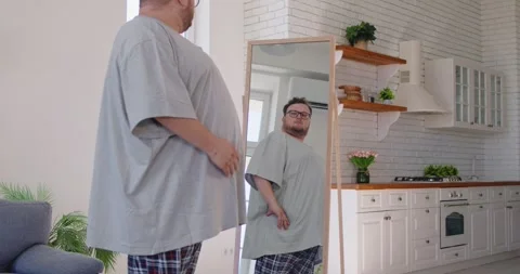 Overweight happy man posing in front of mirror at home, looking at reflection Vidéo 329289770