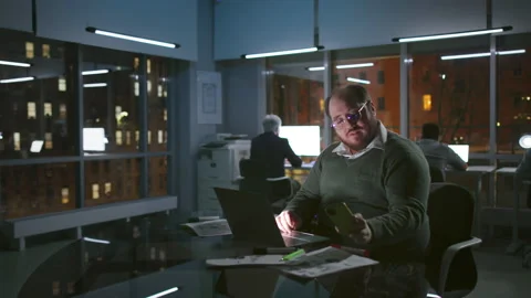 Overweight happy manager work late and use cellphone in dark loft office with Stock Footage 176194466