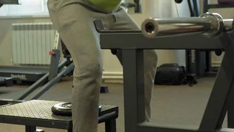 The overweight man does squats with squats with a weight disc for a barbell Video stock 107507168