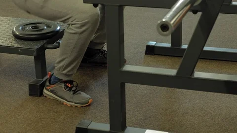 The overweight man does squats with squats with a weight disc for a barbell Video stock 107507513