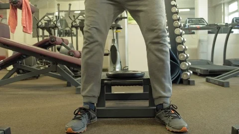 The overweight man does squats with squats with a weight disc for a barbell Video stock 107756069