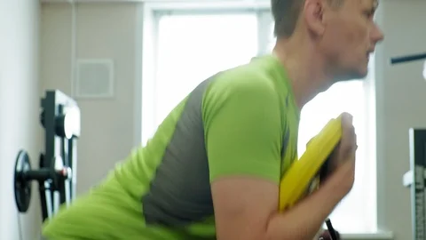 The overweight man does squats with squats with a weight disc for a barbell Video stock 108135099