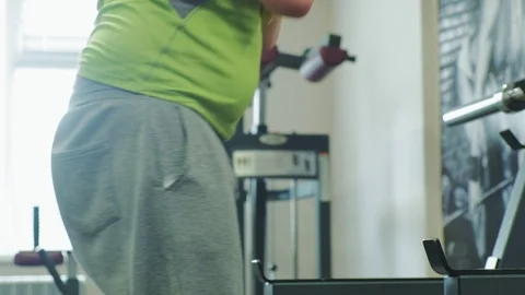The overweight man does squats with squats with a weight disc for a barbell Stock Footage 108135213