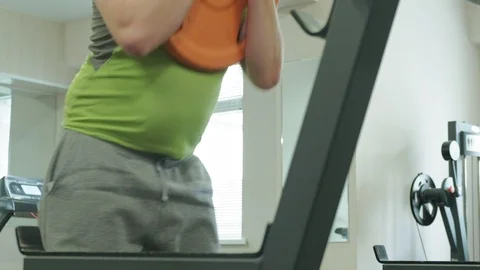 The overweight man does squats with squats with a weight disc for a barbell Video stock 108135245