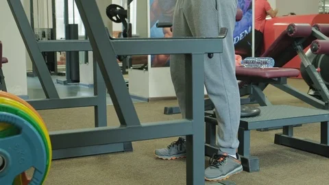 The overweight man does squats with squats with a weight disc for a barbell Video stock 108135878