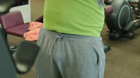 The overweight man does squats with squats with a weight disc for a barbell Video stock 108136381
