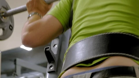The overweight man does squats with squats with a weight disc for a barbell Video stock 111888027