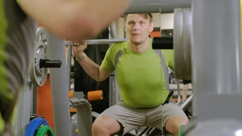 The overweight man does squats with squats with a weight disc for a barbell Video stock 111888142