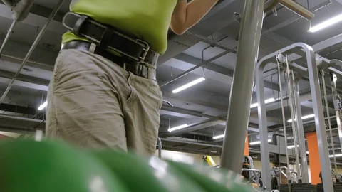 The overweight man does squats with squats with a weight disc for a barbell Video stock 111888257